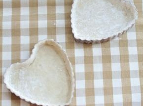 将飞饼皮覆盖在心形派盘上，将面皮与模具按紧，去掉多余的面皮。