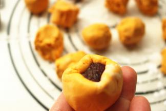 取一个糯米面团，搓圆中间捏出小窝，把豆沙放入，用手捏紧收口，揉圆。