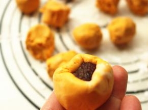 取一个糯米面团，搓圆中间捏出小窝，把豆沙放入，用手捏紧收口，揉圆。