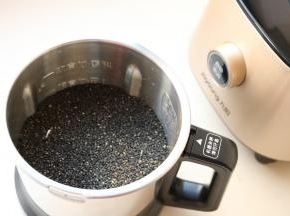 炒熟的黑芝麻放入破壁调理机的不锈钢干磨杯里。