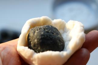 糯米面团按扁，包入冻硬的黑芝麻陷，收紧收口。