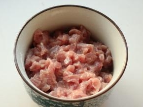 里脊肉切末，加入少许湿淀粉抓匀，加入少许鸡粉和花生油腌制一会。
