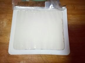 豆腐，打开盒子，倒扣在菜板上，取下盒子，将豆腐切块。