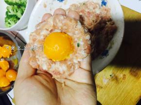 5. 取一些肉泥在手中摊成饼，放入蛋黄，包起来。