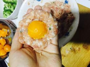 5. 取一些肉泥在手中摊成饼，放入蛋黄，包起来。