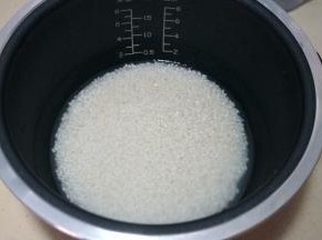 2.	适量的大米入电饭煲内胆中，根据自家食用量来定，清洗两遍后加凉水，水量比你家平时焖饭的水量少三分之一；