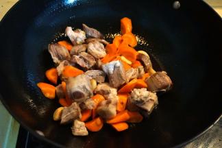 4.	炒锅中倒一点点油，大蒜煸炒出香味后将排骨和胡萝卜入锅中翻炒；