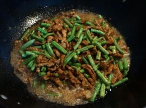 5.将豇豆倒入锅中，翻炒均匀后，倒入热水，与菜料持平即可，转小火，焖几分钟；