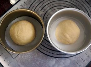 然后分成约300克一个的面团，揉圆，分别放入6寸的圆形蛋糕模具中，盖上保鲜膜，保鲜膜上刺几个小孔。