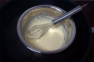 在烤面包的过程中，制作奶酪馅。先把牛奶加入到奶油奶酪中，然后隔水加热搅拌至顺滑状态。