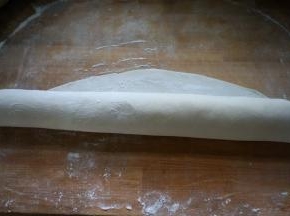 8.擀面杖从底边向上卷起，一边卷一边压，使面片变得越来越薄、越来越大；可把四边都分别这样重复几次；