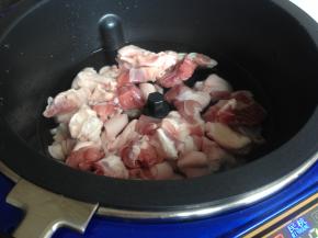 将猪蹄放进锅里。点击一下开关电源，炒菜锅自动加热3分钟。预热完毕后，选择“蒸炖”，时间8分钟