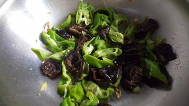 14.把青椒块和木耳，放入锅中煸炒。