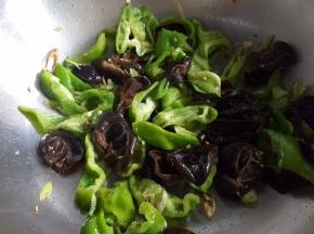 14.把青椒块和木耳，放入锅中煸炒。