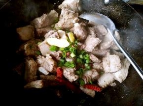 放油之后继续煸炒片刻放入葱姜，大料和干辣椒，花椒粉爆香。
