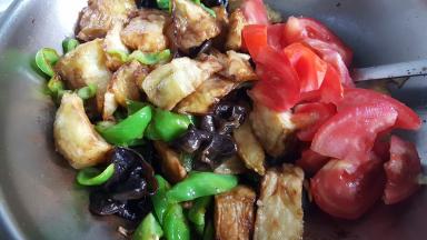 15.加入茄子块和番茄块一同炒，这时可以加适量的新盐和酱油进行调味。