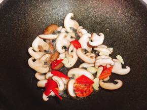 锅烧热倒入适量油，加入蒜片、红彩椒一起爆香，放入香菇片煸至断生