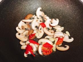 锅烧热倒入适量油，加入蒜片、红彩椒一起爆香，放入香菇片煸至断生