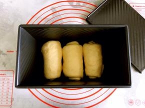 取一个面团擀成长椭圆形，左右边对折，底边压薄，从上往下卷起。其他两个面团也依次卷好。放在学厨吐司盒中。