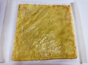 将泡芙皮移至大油纸上，泡芙皮涂抹炼乳奶油霜