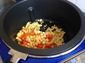 炒菜机加热后，选择炒菜功能，时间八分钟，锅里加油，放入玉米胡萝卜。