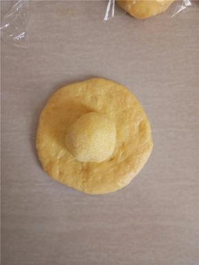 取松弛好的小面团压扁，包入椰蓉馅。