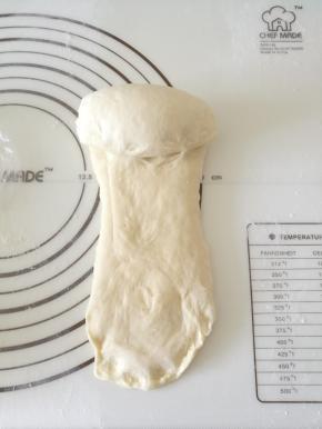 醒好的面团竖向擀成长条状，宽度不要超过模具宽度，翻面从上往下卷成卷