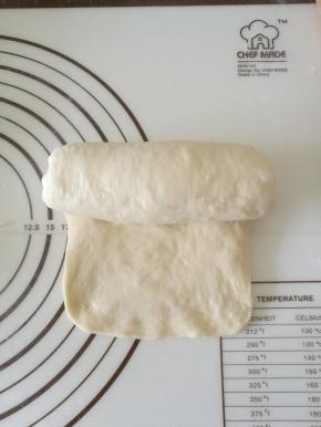 把醒好的面团擀成长条，翻面，从上往下卷成卷