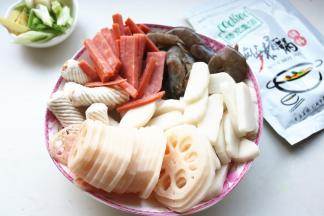 处理一下食材，火腿肠切细条，虾挑去虾线，莲藕去皮切片，年糕切片。