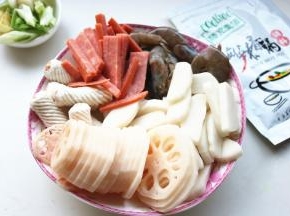 处理一下食材，火腿肠切细条，虾挑去虾线，莲藕去皮切片，年糕切片。
