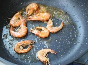 炒锅下油，油热后下入虾煎香两面。