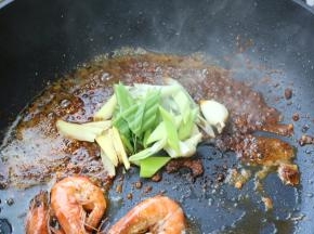 把虾推到一边，下入麻辣香锅底料继续炒。炒香麻辣香锅底料后，下入葱姜蒜继续炒出香味来。