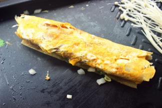 借助铲子和烧烤夹把冷面卷起来。