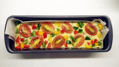 倒入铺好油纸的磅蛋糕模具中，震几下。摆上装饰的圣女果和彩椒。