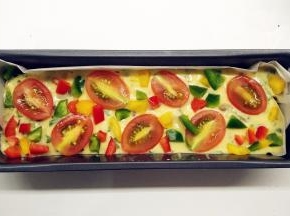 倒入铺好油纸的磅蛋糕模具中，震几下。摆上装饰的圣女果和彩椒。