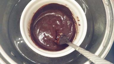 首先我们来做巧克力甘纳许。把巧克力和淡奶油倒入一个小碗中，隔水加热，用手动打蛋器搅拌均匀，直到它们融化。