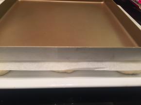 准备一个烤盘，在面包胚上垫一张油纸，将烤盘放在上面，轻轻按压一下