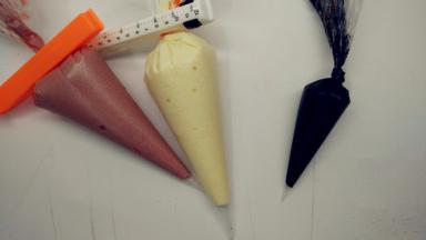 取出刚刚1小勺的原色面糊放在碗中，加入竹炭粉，翻拌均匀，成为黑色面糊。分别将三种颜色的面糊装进裱花袋中。