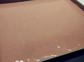 取出烤盘，将红色面糊倒入烤盘中，用刮刀稍微抹平，再震两下。