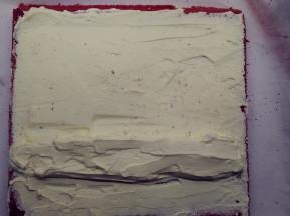 用抹刀在蛋糕体上均匀的抹上一层奶油馅，然后在离自己较近的一侧1/3处用奶油馅堆砌一个小山丘。