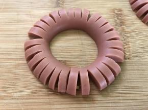 切好的火腿肠圈成一个圈，头尾用牙签固定。
6、烤盘中刷油。