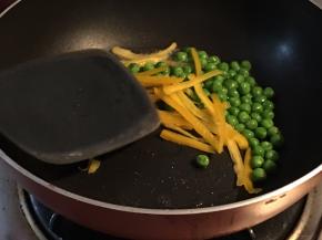 平底锅倒入橄榄油，放入青豆和彩椒丝，放入适量盐翻炒