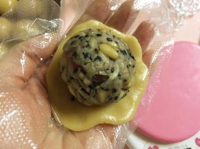 取一块饼皮面团，压扁，放上五仁馅