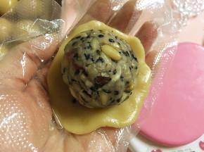 取一块饼皮面团，压扁，放上五仁馅