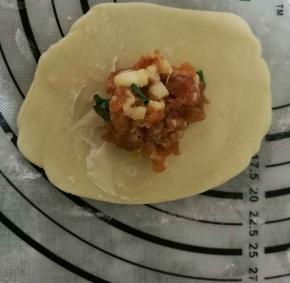 擀开后包住15克馅料，收口向下搓圆