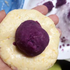 取35g南瓜面团搓圆、压扁，放入15g紫薯馅。