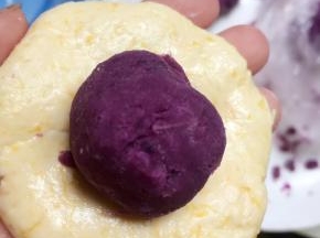 取35g南瓜面团搓圆、压扁，放入15g紫薯馅。