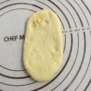 取一松弛好面团，按扁，擀成椭圆形。