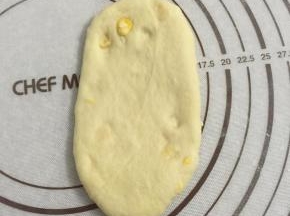 取一松弛好面团，按扁，擀成椭圆形。