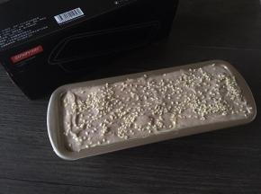 倒入21cm长方形蛋糕模具，抹平表面后撒上白芝麻